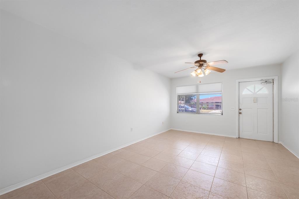 An empty room features light-colored tile flooring, a ceiling fan, and a white entry door — 3775 59TH STREET N UNIT 2, ST PETERSBURG, FL