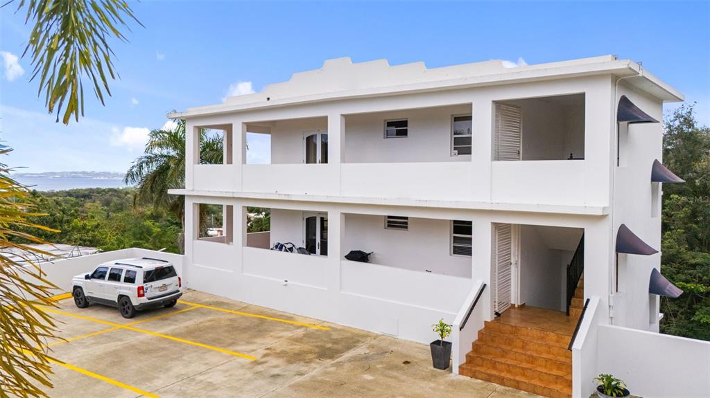 A two-story white building with open balconies and a paved parking area in front — 3rd Floor PUNTA LIBERTAD CONDOMINIO UNIT 3, RINCON, PR