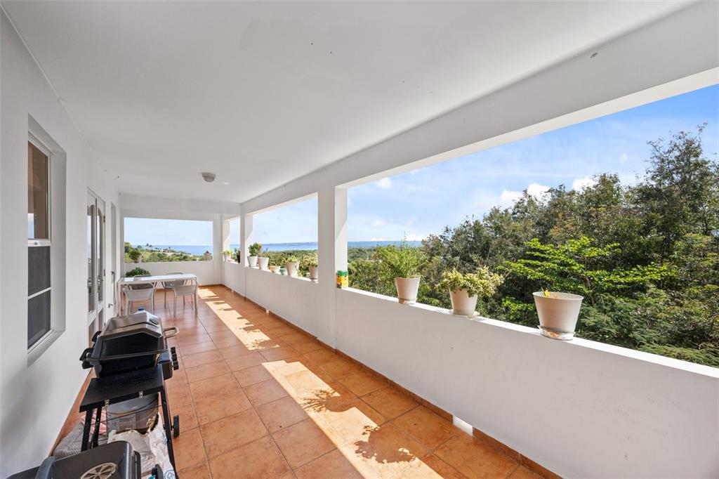 A long, covered balcony with terracotta tile flooring, a grill, and views of the ocean — 3rd Floor PUNTA LIBERTAD CONDOMINIO UNIT 3, RINCON, PR