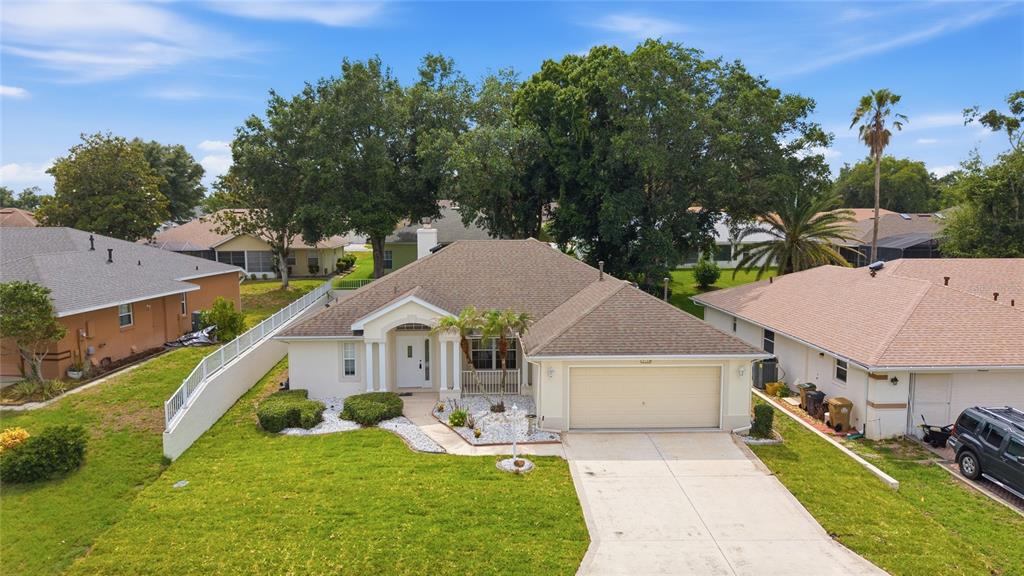 An aerial view of a single-story suburban house with a tan exterior and two-car garage — 5133 LINKS LANE, LEESBURG, FL