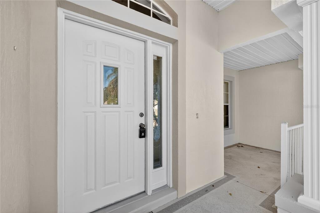 A white front door with a glass insert and sidelight sits on a covered porch — 5133 LINKS LANE, LEESBURG, FL