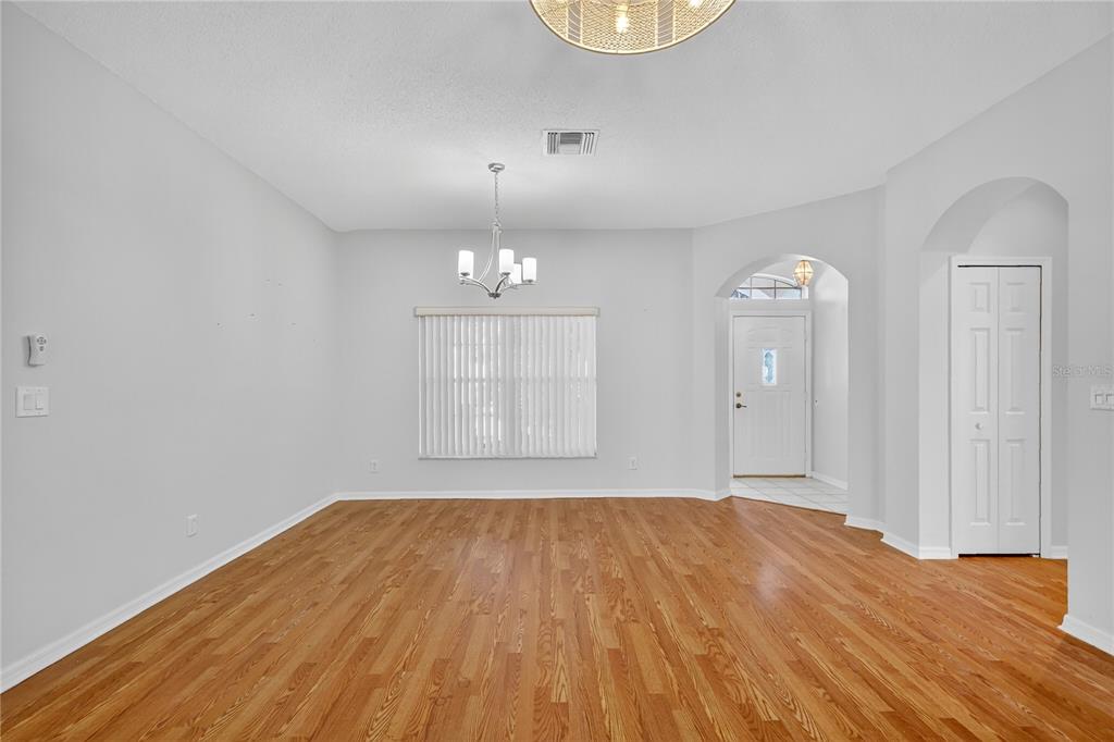 An empty dining room with hardwood floors, a chandelier, and an arched entryway — 5133 LINKS LANE, LEESBURG, FL