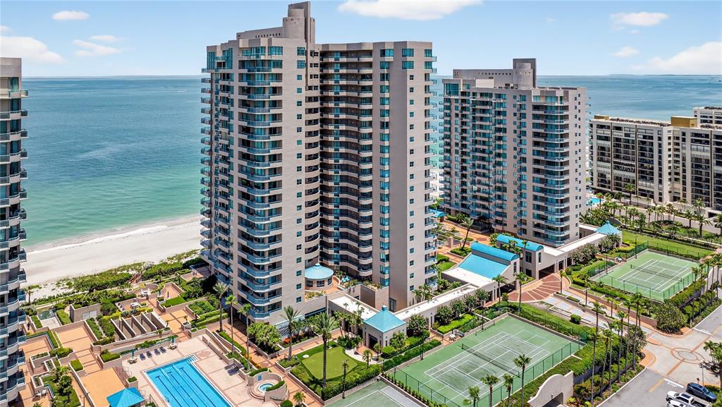 An aerial view of high-rise beachfront condominiums featuring swimming pools and tennis courts — 1540 GULF BOULEVARD UNIT 2107, CLEARWATER BEACH, FL