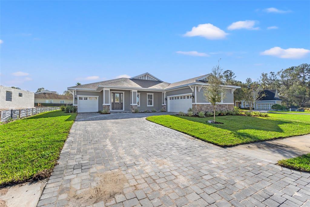 A single-story house with a gray exterior, stone accents, and a paved driveway — 19486 SHELTERED HILL DRIVE, BROOKSVILLE, FL