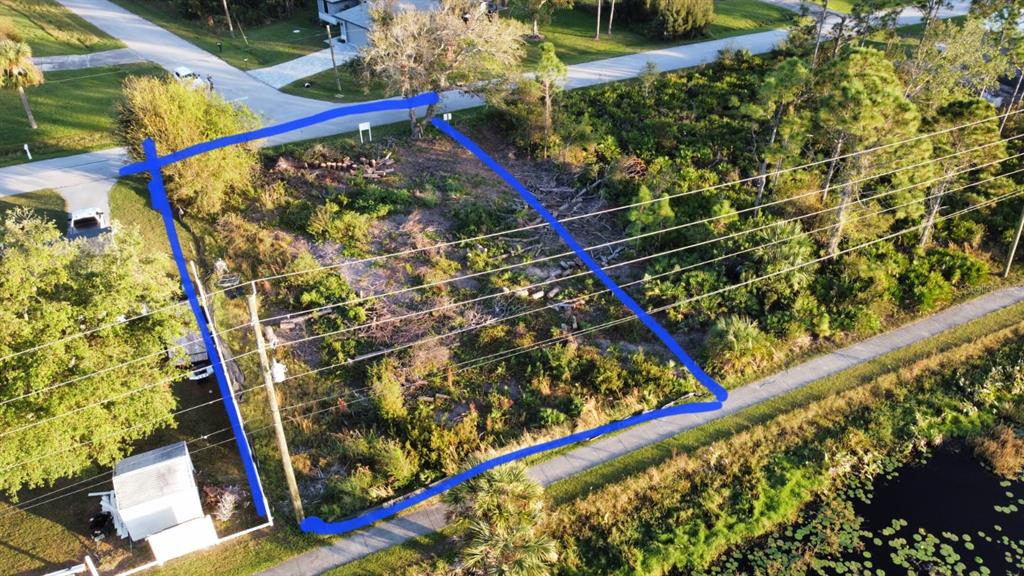 An aerial view shows a vacant, partially cleared residential lot bordered by a road and canal — 3419 SWANEE ROAD, PORT CHARLOTTE, FL