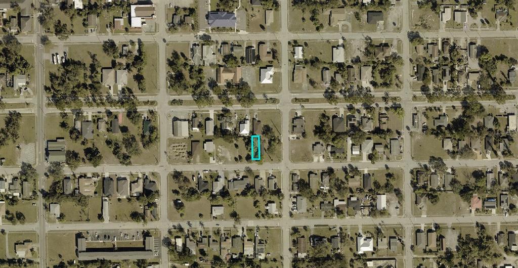 An aerial view of a residential neighborhood with a vacant lot highlighted in blue — 2989 DUNBAR AVENUE, FORT MYERS, FL