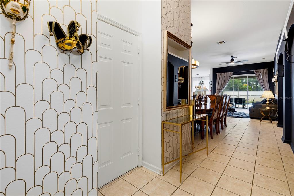 A hallway with patterned wallpaper leads to a dining area and living room with tile floors — 8066 KING PALM CIRCLE, KISSIMMEE, FL