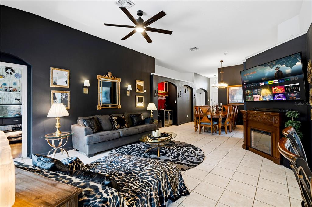 A living room features dark walls, a leopard-print chaise, a fireplace, and an adjacent dining area — 8066 KING PALM CIRCLE, KISSIMMEE, FL