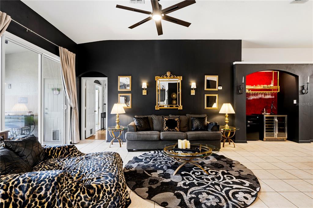 A living room features black walls, a grey sofa, a leopard-print chair, and a bar area — 8066 KING PALM CIRCLE, KISSIMMEE, FL