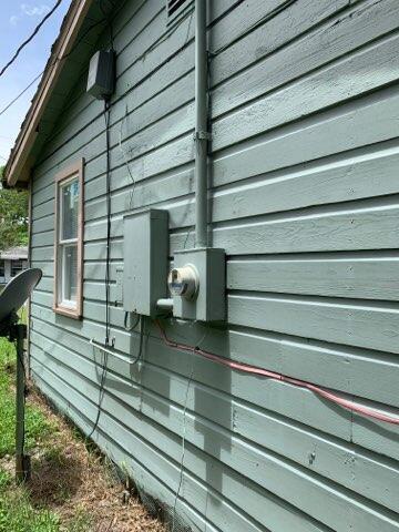 The exterior wall of a house features green siding, an electrical meter, and utility boxes — 242 A Lane, Cocoa FL 32926, COCOA, FL