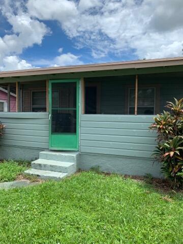 A light green house exterior features a bright green screen door and concrete steps — 242 A Lane, Cocoa FL 32926, COCOA, FL