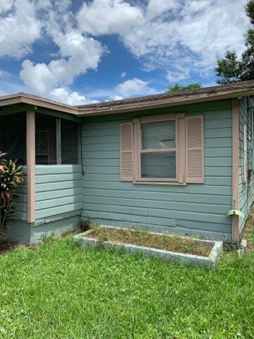 The exterior of a light green house features horizontal siding, a window with shutters, and landscaping — 242 A Lane, Cocoa FL 32926, COCOA, FL