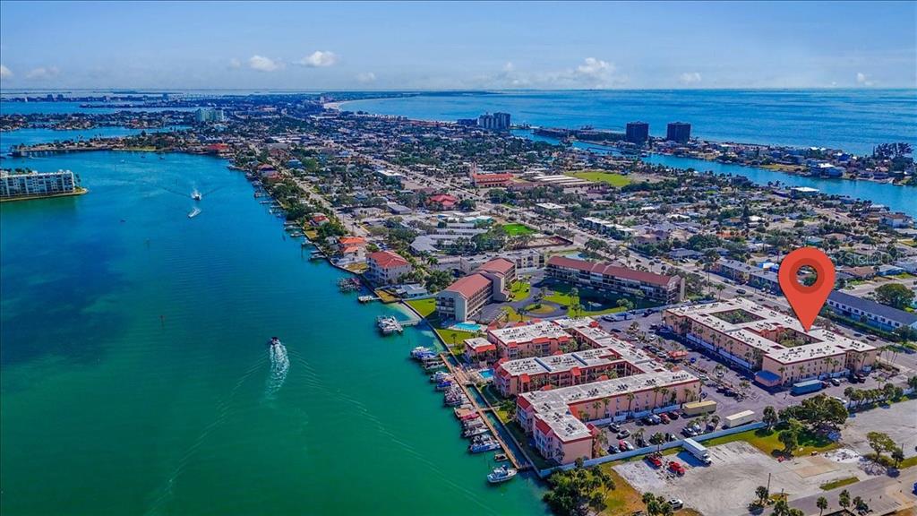 An aerial view shows a waterfront apartment complex with a red location pin — 8911 BLIND PASS ROAD UNIT 209, ST PETE BEACH, FL