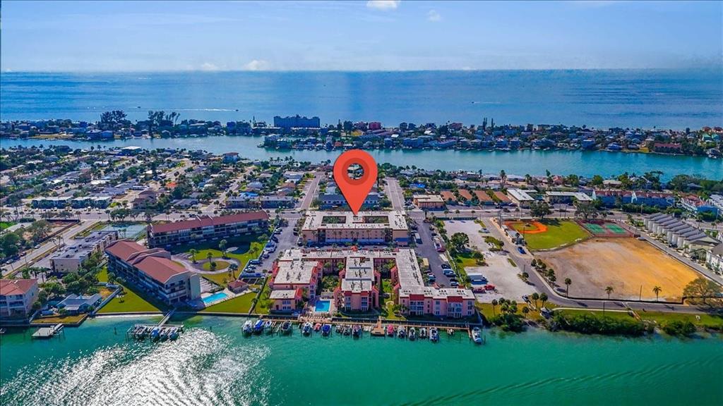 An aerial view shows a waterfront apartment complex with a red map pin marker — 8911 BLIND PASS ROAD UNIT 209, ST PETE BEACH, FL