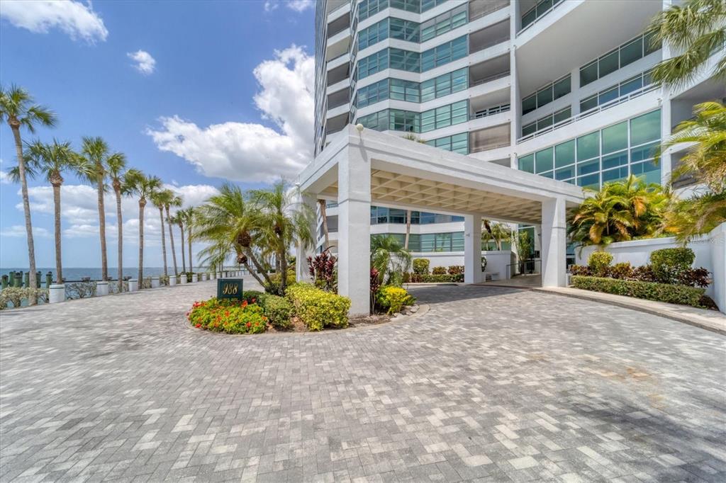 A paved circular driveway leads to the covered entrance of a modern high-rise building — 988 BLVD OF THE ARTS UNIT 1816, SARASOTA, FL