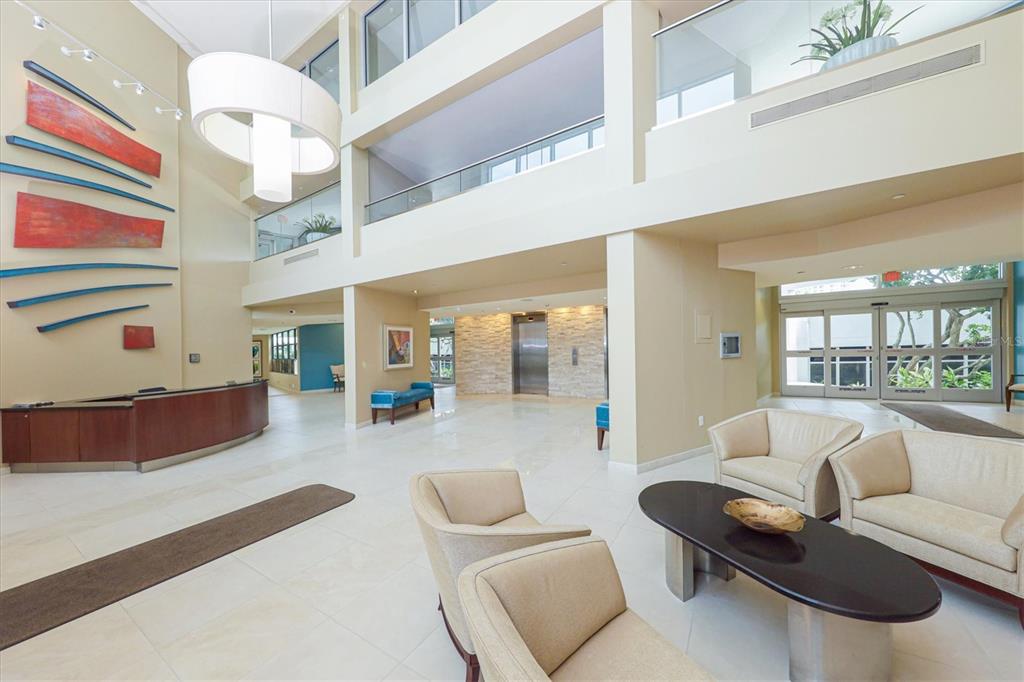 A spacious lobby features a reception desk, seating area, elevator, and high ceilings — 988 BLVD OF THE ARTS UNIT 1816, SARASOTA, FL