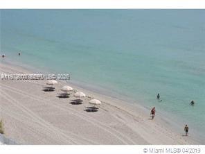 An elevated view of a sandy beach with several umbrellas and people swimming in water — 3535 S Ocean Dr # 905, Hollywood FL 33019, HOLLYWOOD, FL