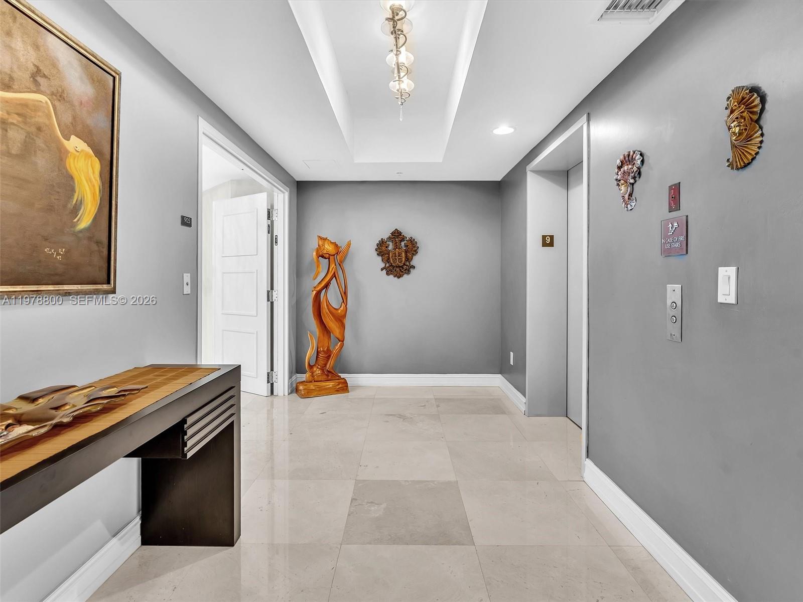 A hallway features gray walls, tile flooring, a wooden sculpture, and an elevator entrance — 3535 S Ocean Dr # 905, Hollywood FL 33019, HOLLYWOOD, FL
