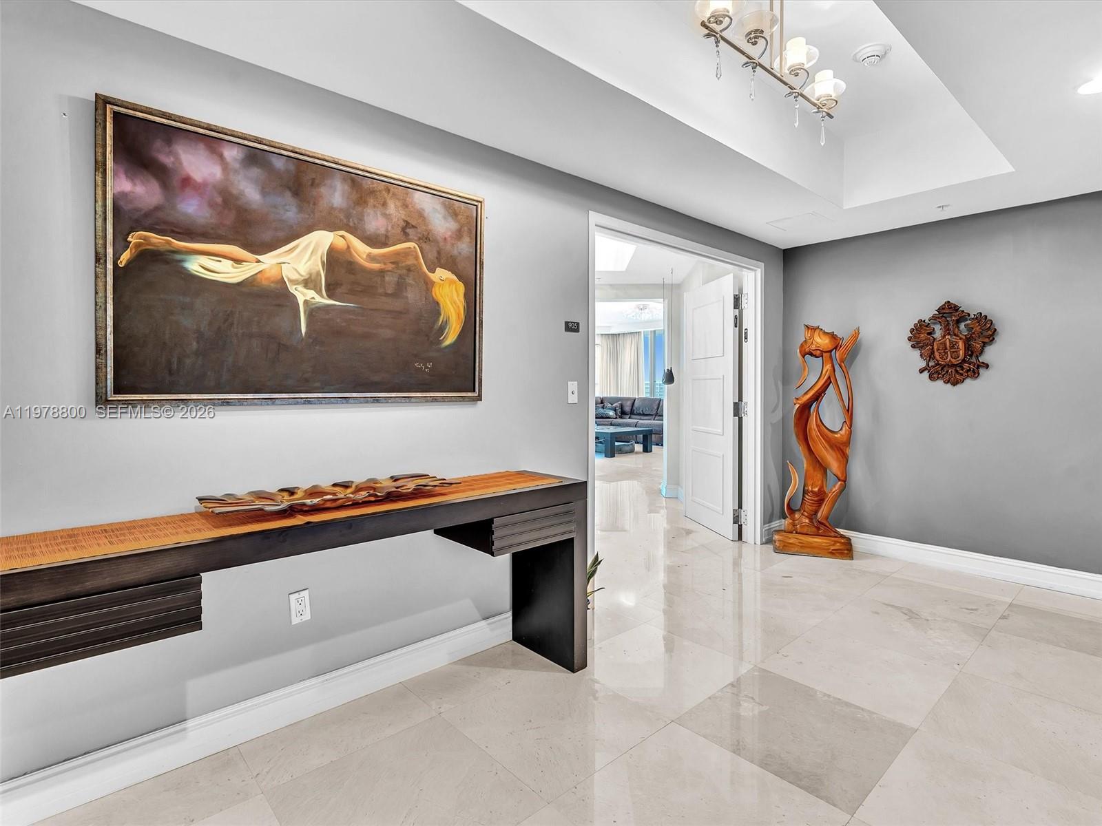 A foyer features a long console table, a large painting, and a wooden sculpture — 3535 S Ocean Dr # 905, Hollywood FL 33019, HOLLYWOOD, FL