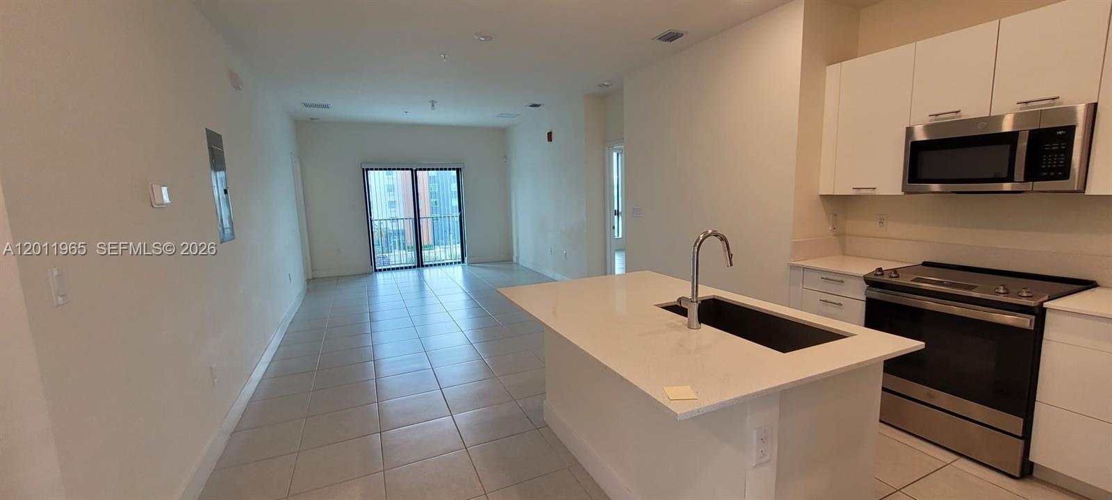 A kitchen with white cabinets and a central island overlooks an open living area — 8001 NW 41st St # 405, Doral FL 33166, DORAL, FL