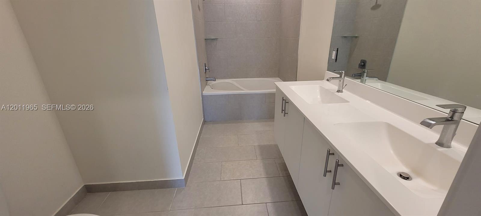 A modern bathroom features a double vanity, white cabinets, and a tiled bathtub-shower combination — 8001 NW 41st St # 405, Doral FL 33166, DORAL, FL
