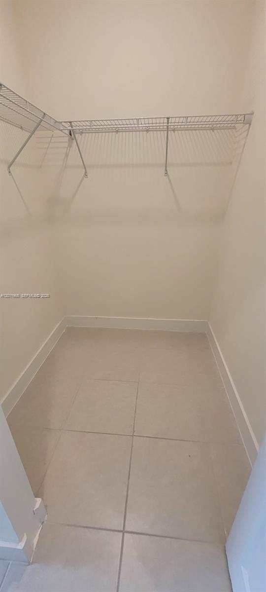 A walk-in closet features white walls, light-colored tile flooring, and wire shelving — 8001 NW 41st St # 405, Doral FL 33166, DORAL, FL