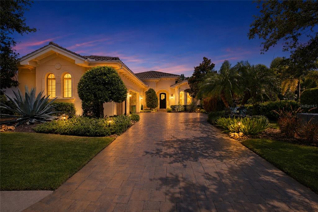A paved driveway leads to the entrance of a single-story house at twilight — 7952 MATERA COURT, LAKEWOOD RANCH, FL