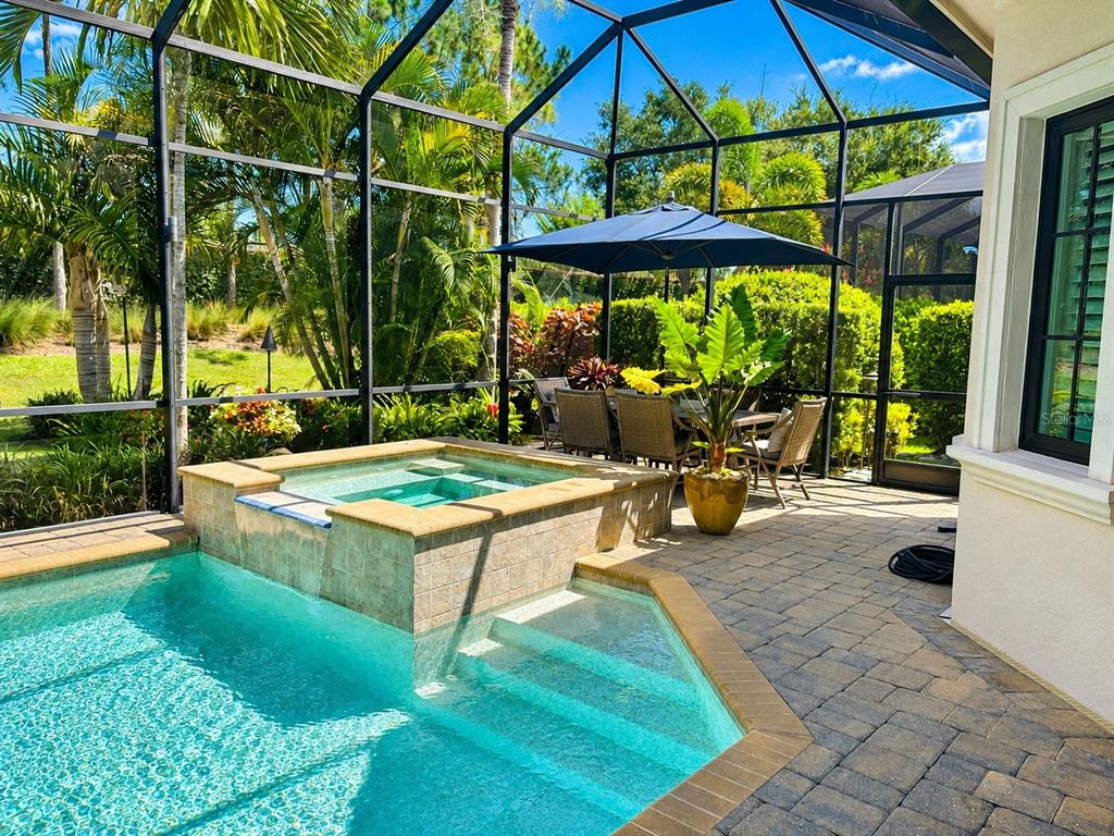 A screened-in patio features a pool with an attached hot tub and outdoor dining area — 7952 MATERA COURT, LAKEWOOD RANCH, FL