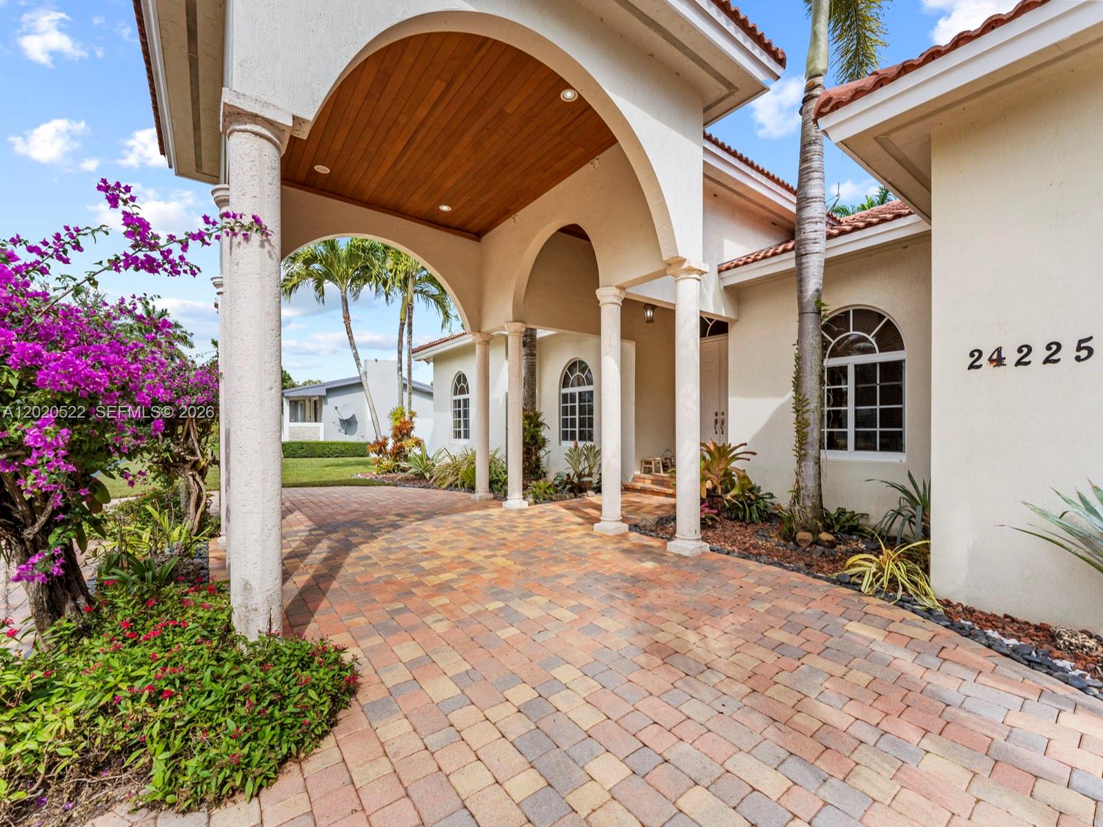A paved driveway leads to a covered entryway with arched openings and stone columns — 24225 SW 198th Ave, Homestead FL 33031, HOMESTEAD, FL