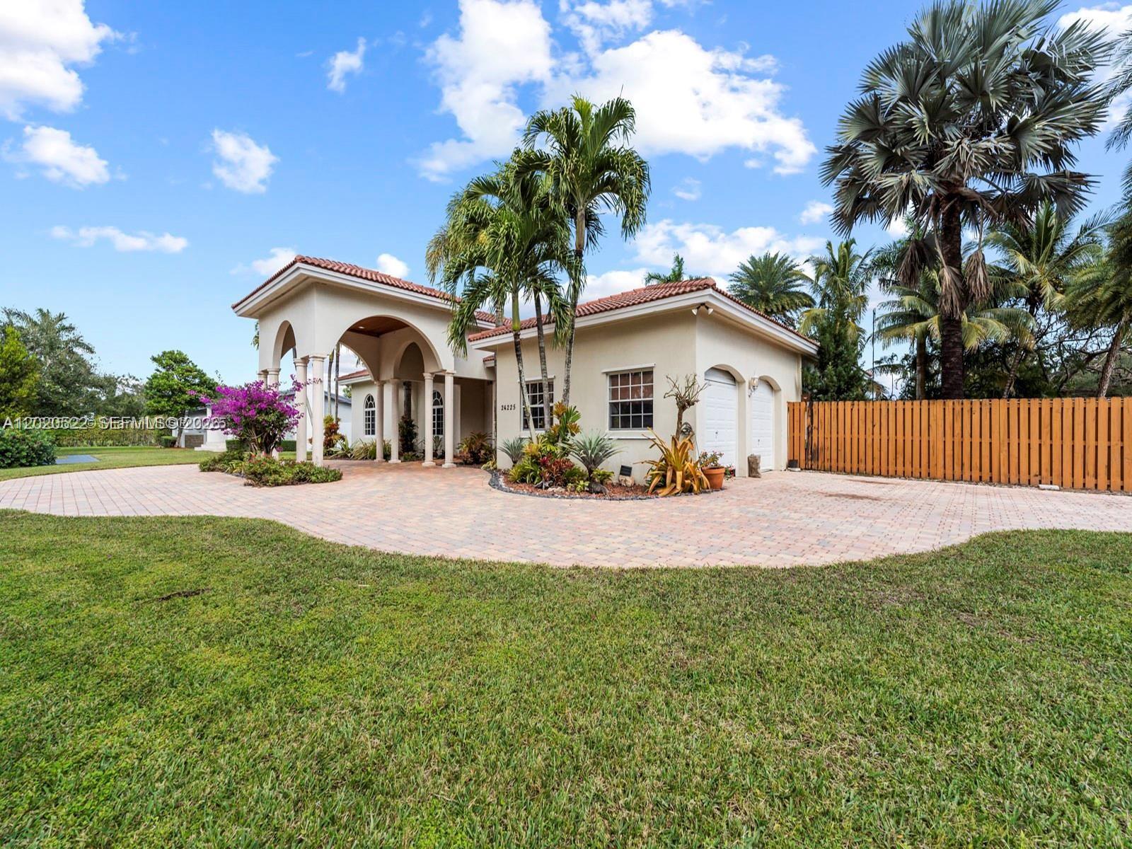 A single-story house features a paved driveway, a covered entryway with arches, and palm trees — 24225 SW 198th Ave, Homestead FL 33031, HOMESTEAD, FL
