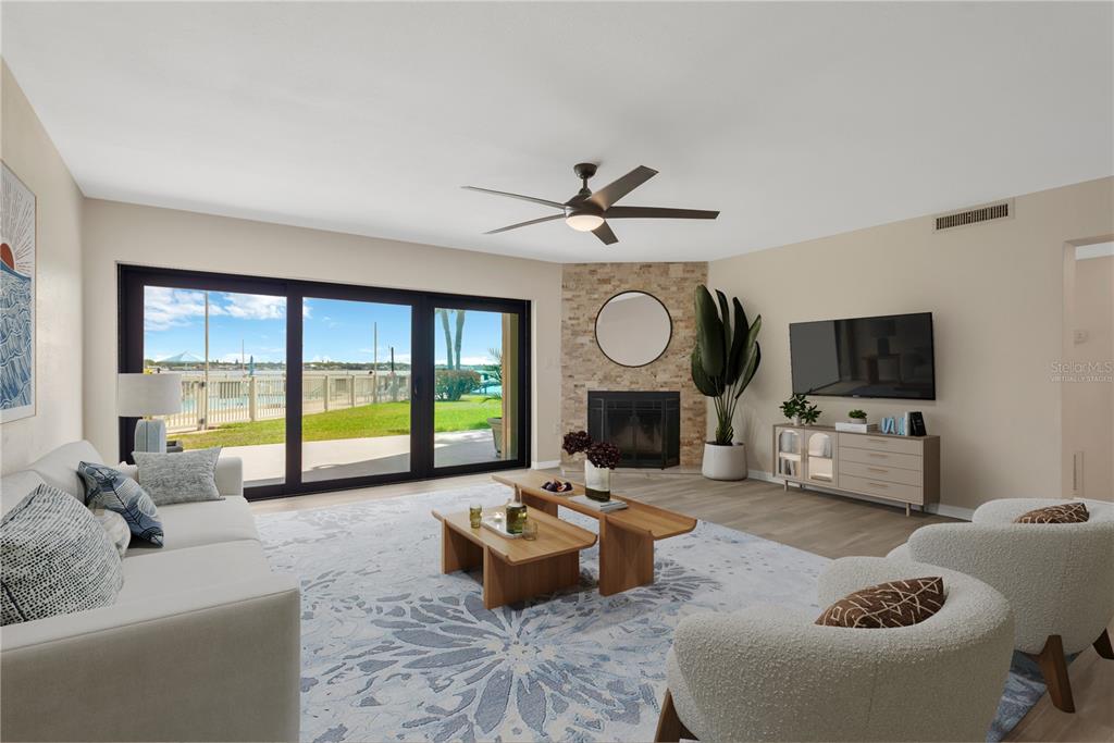 A living room features a stone fireplace, sliding glass doors, and a view of water — 7520 SUNSHINE SKYWAY LANE S UNIT P5, ST PETERSBURG, FL