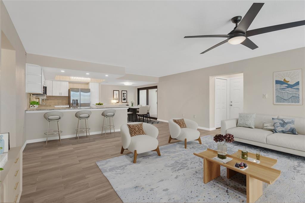 An open-concept living room and kitchen featuring light wood flooring, bar seating, and neutral decor — 7520 SUNSHINE SKYWAY LANE S UNIT P5, ST PETERSBURG, FL