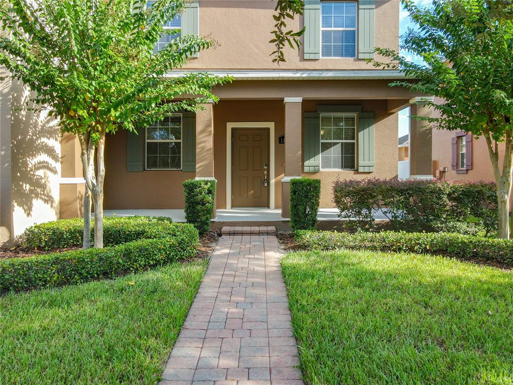 A paved walkway leads to the front entrance of a two-story house with tan siding — 14903 DRIFTWATER DRIVE, WINTER GARDEN, FL