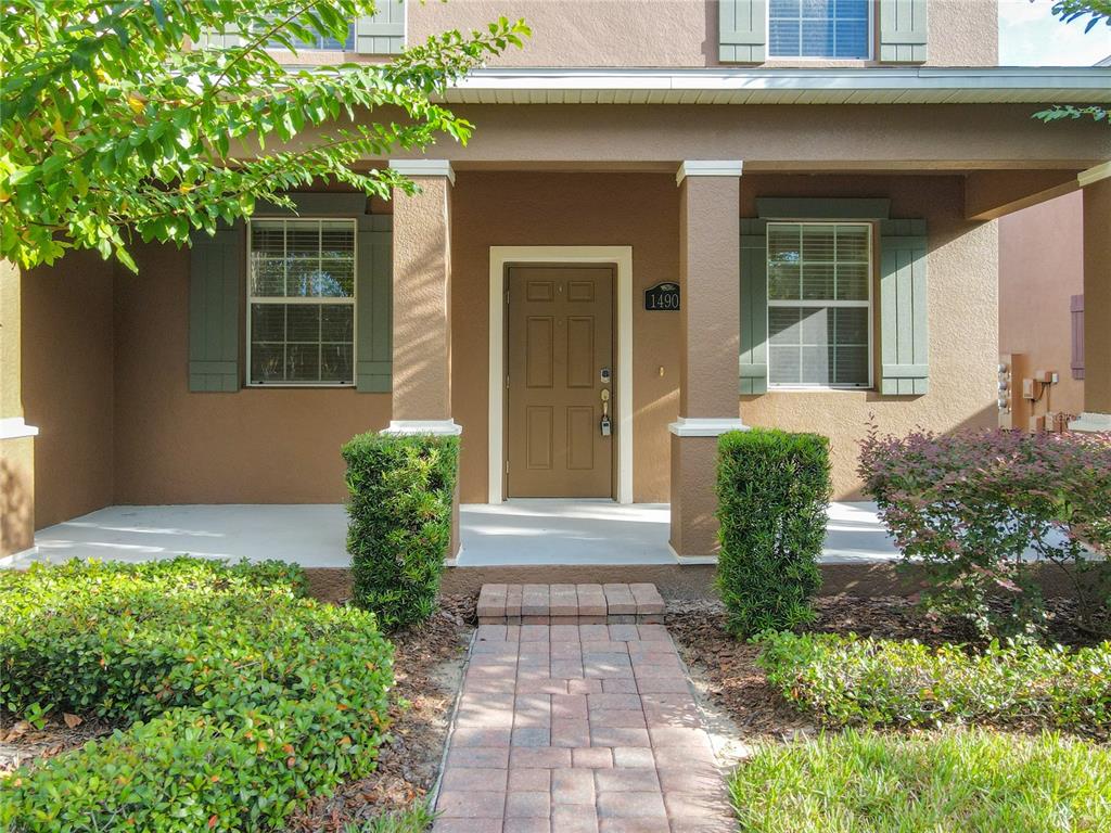 A front entrance features a brown door, a brick walkway, and two trimmed hedges — 14903 DRIFTWATER DRIVE, WINTER GARDEN, FL