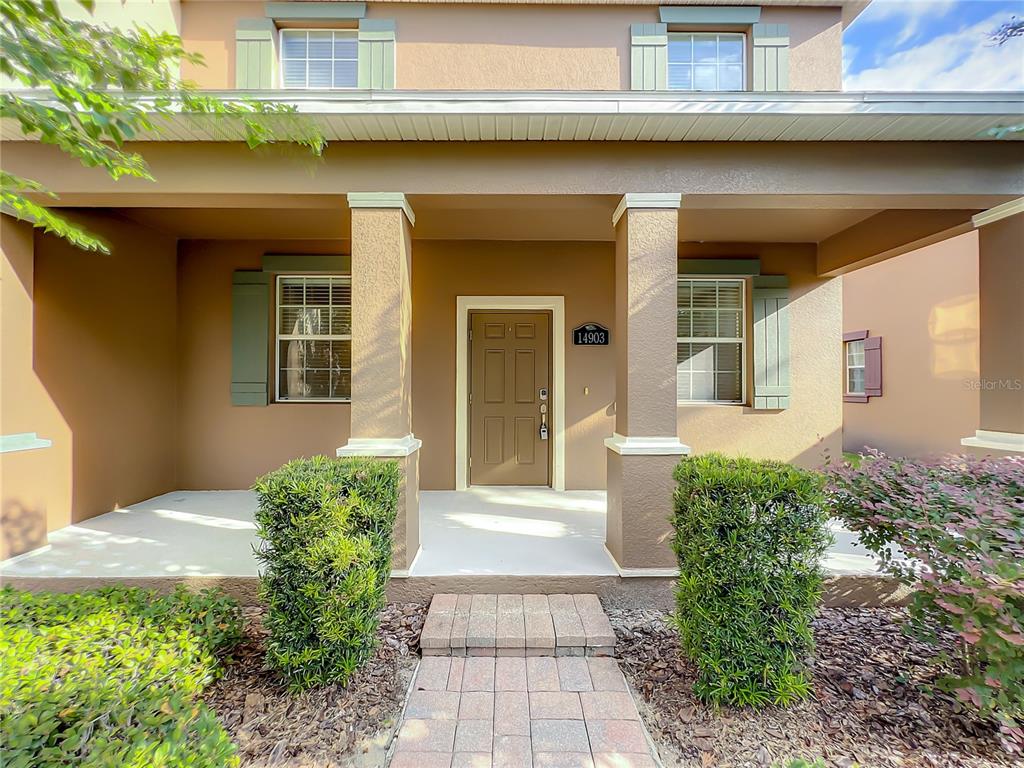 A front porch with two square columns leads to a brown door with a house number — 14903 DRIFTWATER DRIVE, WINTER GARDEN, FL