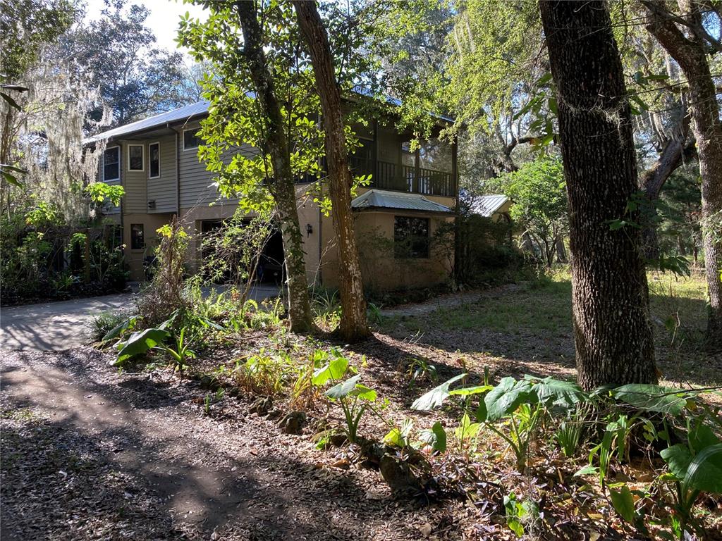 A two-story house with a screened porch and garage sits among trees and foliage — 2436 CR 416N, LAKE PANASOFFKEE, FL