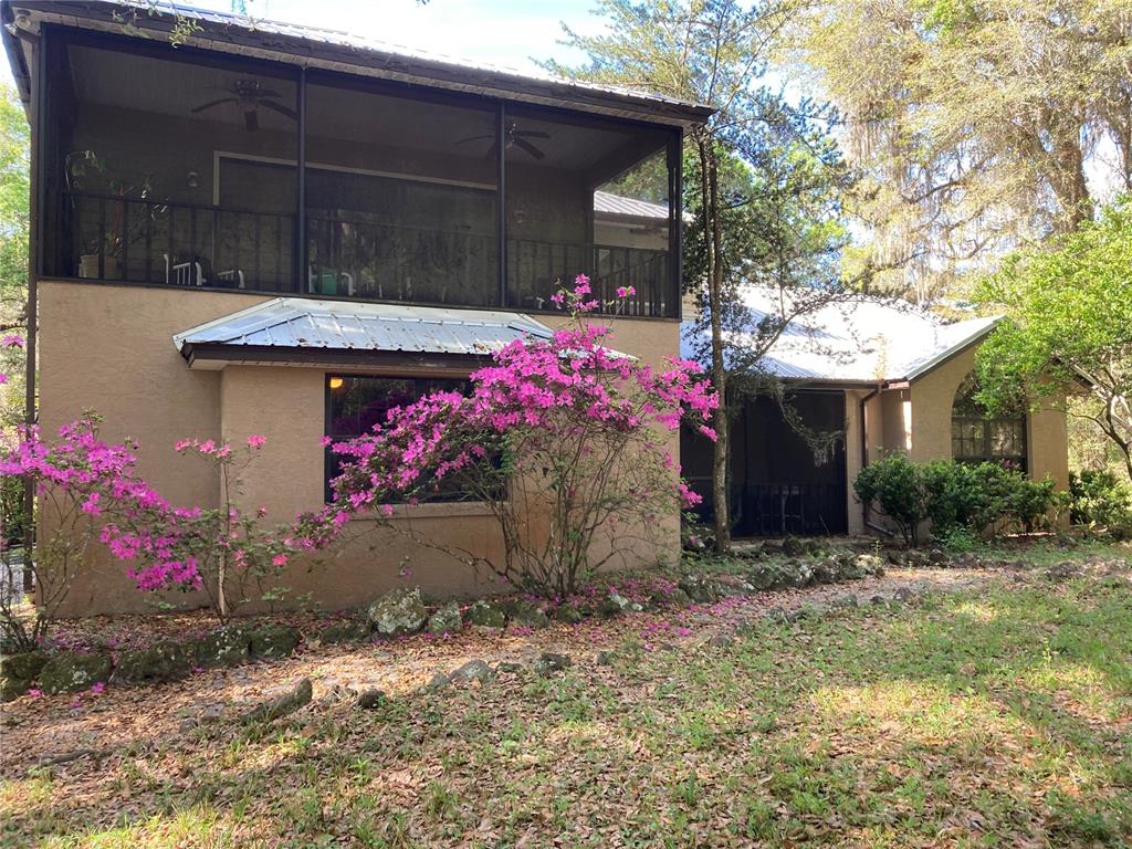 A two-story house features a screened-in porch, a metal roof, and blooming azalea bushes — 2436 CR 416N, LAKE PANASOFFKEE, FL