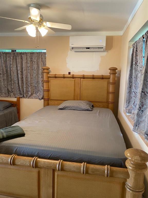 A bedroom features a wooden bed frame, a ceiling fan, and a wall-mounted air conditioner — 1587 WAYMAN ROAD, MOORE HAVEN, FL