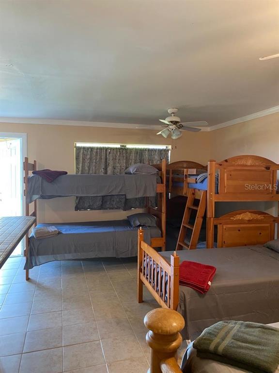 A bedroom features multiple wooden bunk beds and a single bed on a tiled floor — 1587 WAYMAN ROAD, MOORE HAVEN, FL