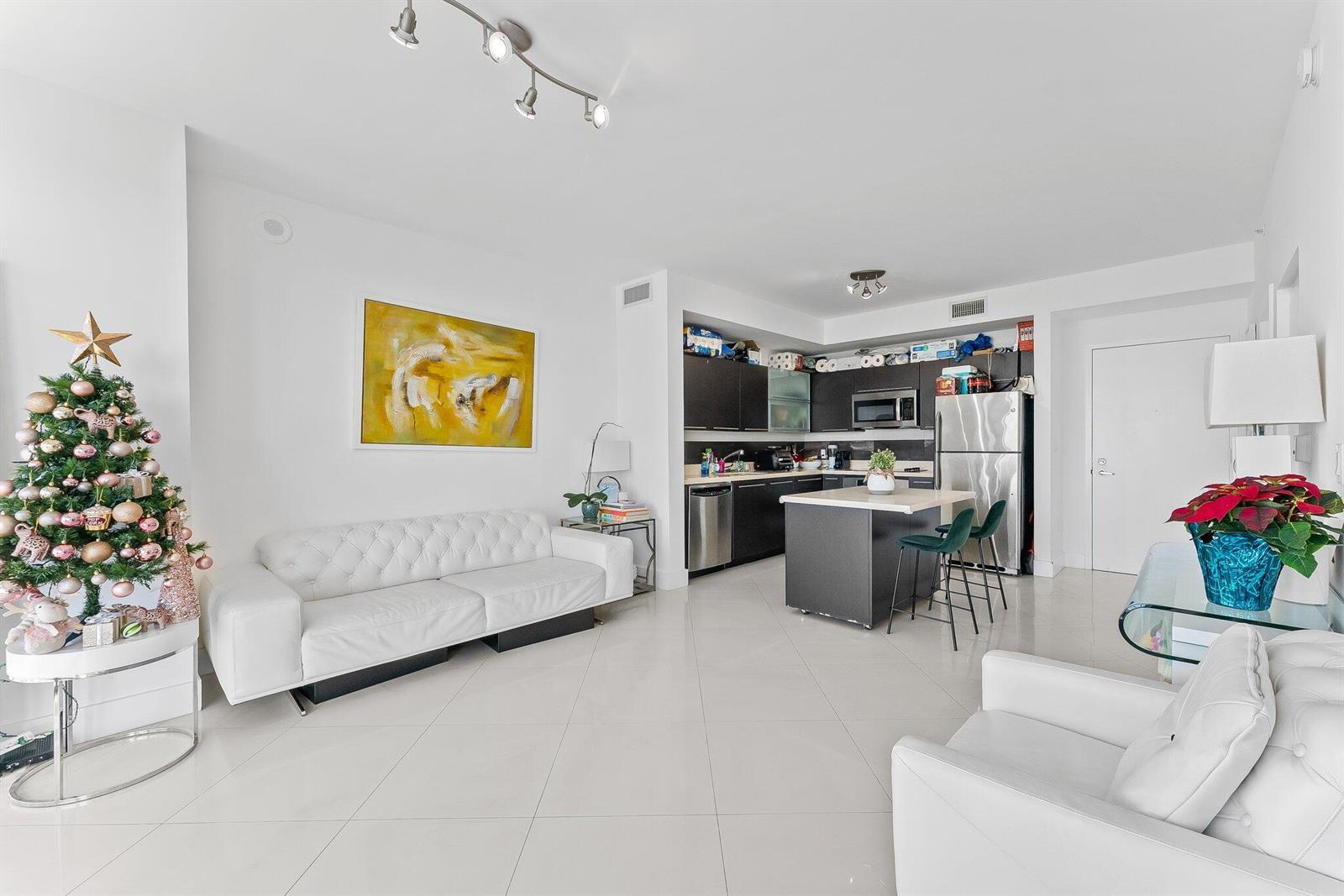 A modern open-concept living room and kitchen with white tile floors and a Christmas tree — 90 SW 3rd Street # 1410, Miami FL 33130, MIAMI, FL