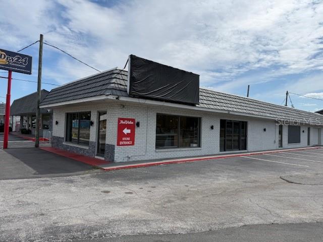 A single-story commercial building with a white brick exterior and a dark shingled roof — 9501 N NEBRASKA AVENUE, TAMPA, FL