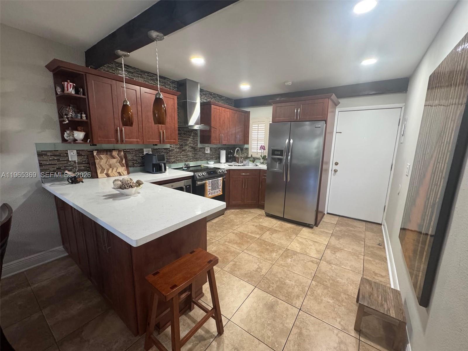 A kitchen features cherry wood cabinets, white countertops, stainless steel appliances, and tile flooring — 5500 SW 77th Ct # 305, Miami FL 33155, MIAMI, FL