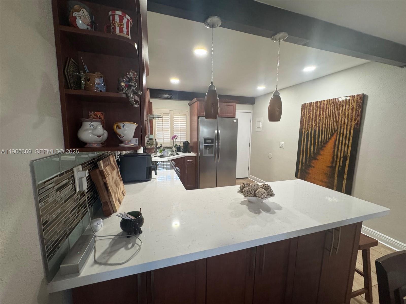 A kitchen features a white quartz peninsula, dark wood cabinetry, and two hanging pendant lights — 5500 SW 77th Ct # 305, Miami FL 33155, MIAMI, FL