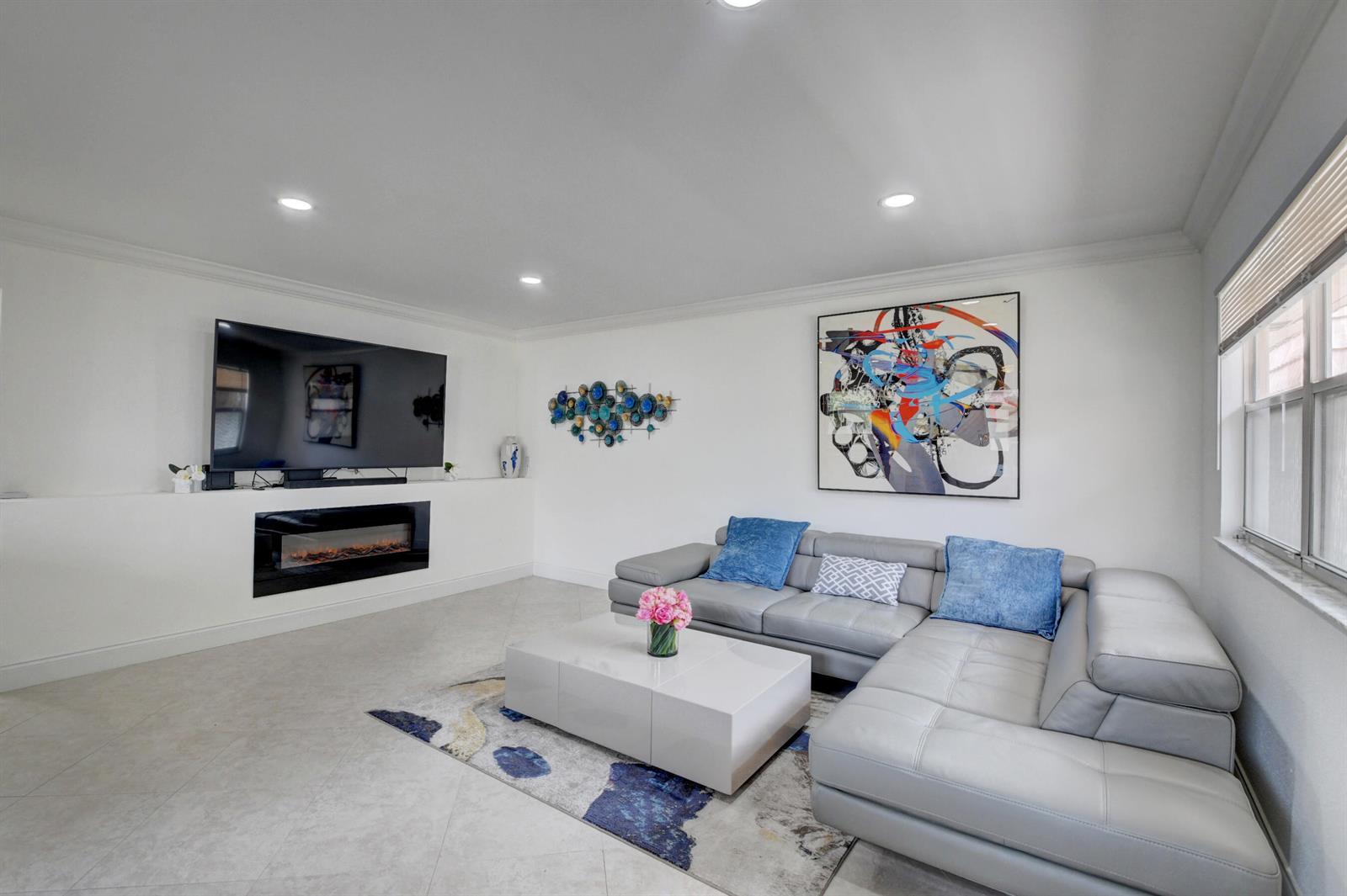 A modern living room features a grey sectional sofa, a fireplace, and a television — 468 Saxony Way, Delray Beach FL 33446, DELRAY BEACH, FL
