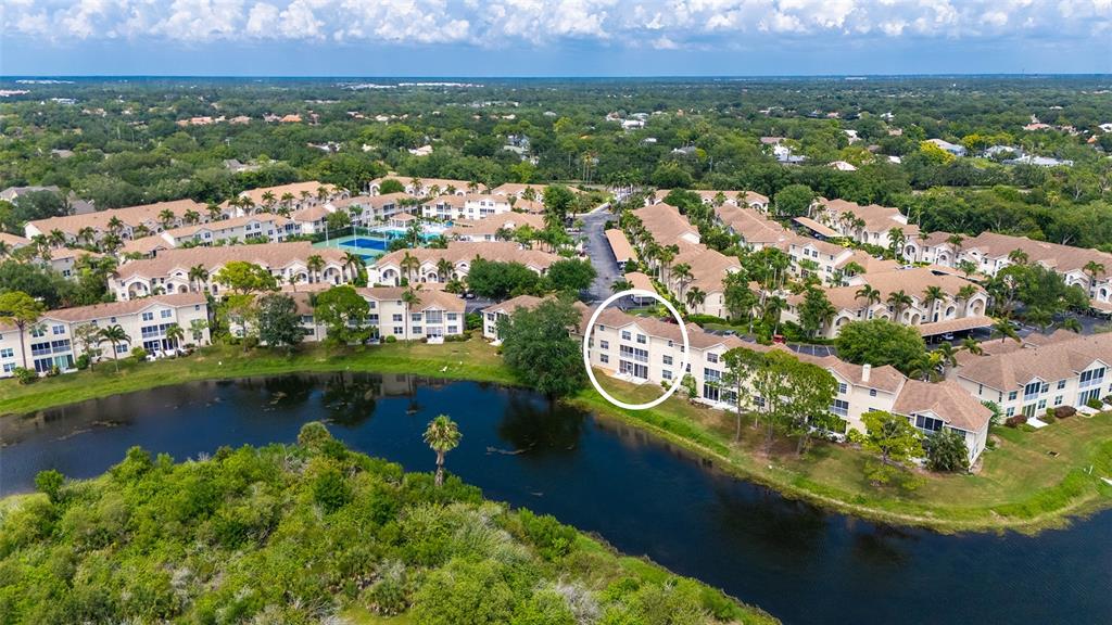 An aerial view shows a multi-story residential building circled near a lake and green space — 8370 WINGATE DRIVE UNIT 716, SARASOTA, FL