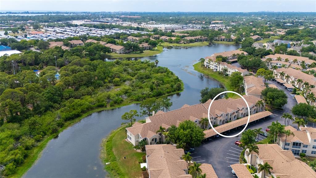 An aerial view shows a multi-story residential building with a brown roof near a lake — 8370 WINGATE DRIVE UNIT 716, SARASOTA, FL