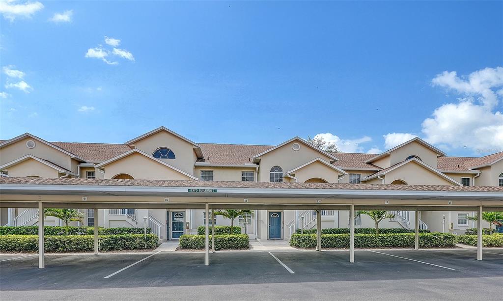A two-story apartment building exterior with a covered parking structure in the foreground — 8370 WINGATE DRIVE UNIT 716, SARASOTA, FL