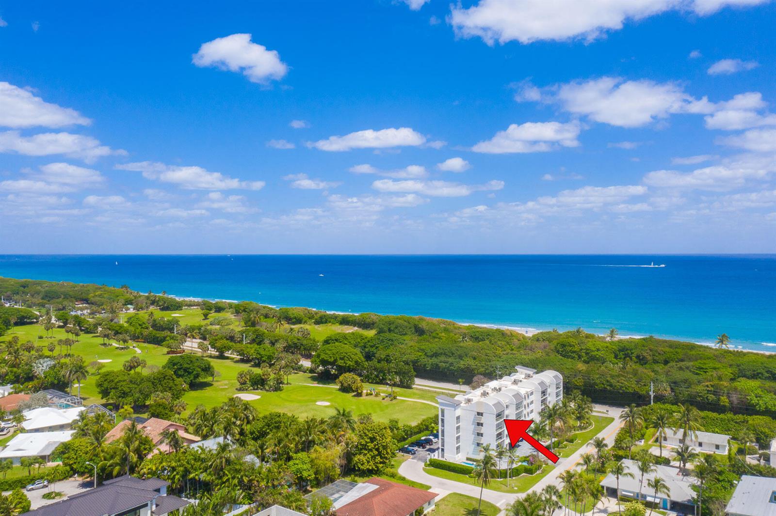 An aerial view shows a multi-story apartment building situated next to a golf course and ocean — 601 N Ocean Boulevard # 203, Boca Raton FL 33432, BOCA RATON, FL