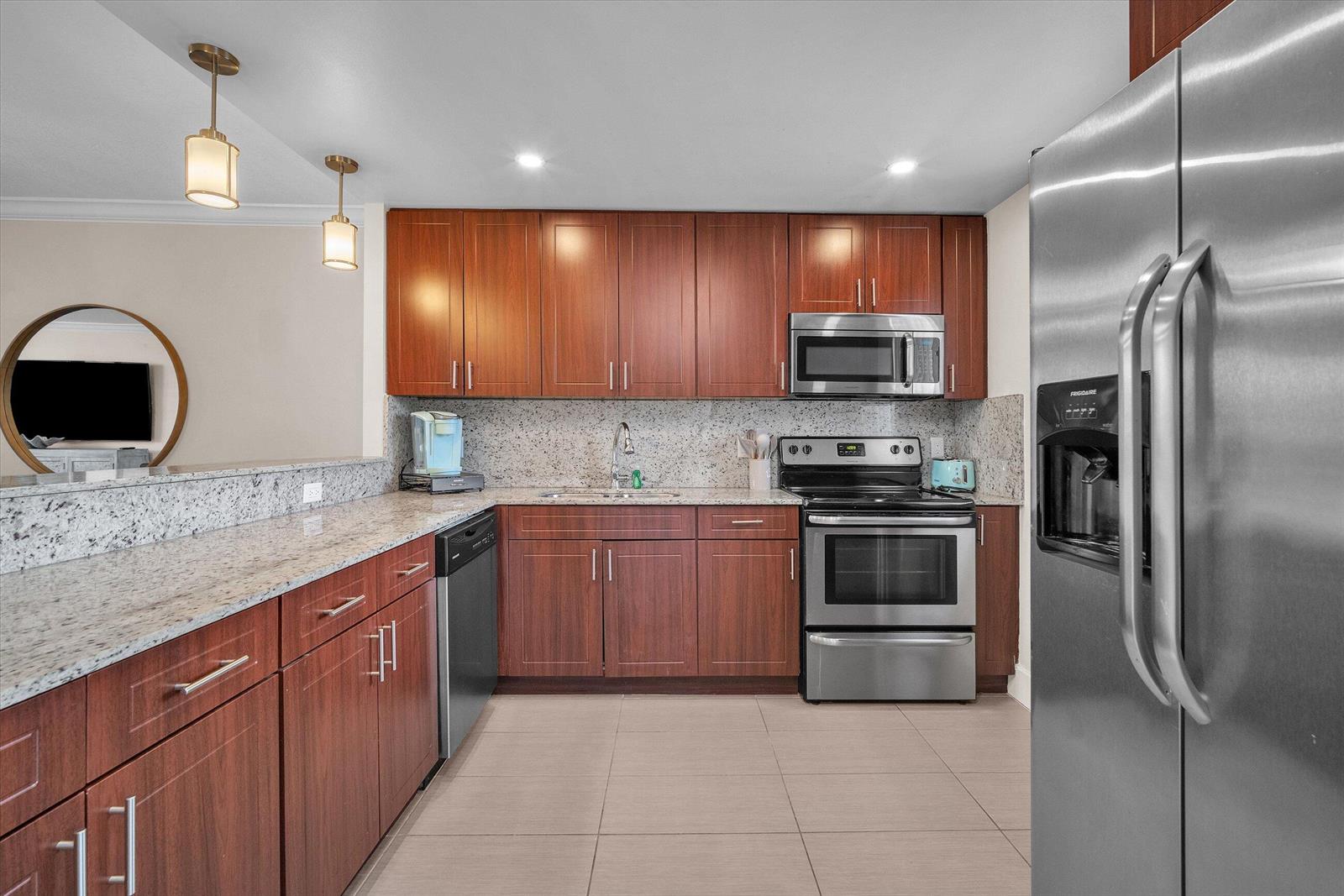 A kitchen features wood cabinets, granite countertops, stainless steel appliances, and tile flooring — 601 N Ocean Boulevard # 203, Boca Raton FL 33432, BOCA RATON, FL