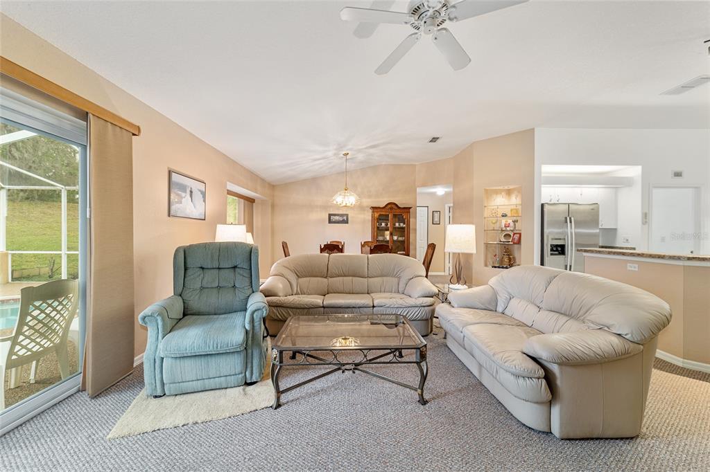 A living room features beige carpet, two light-colored sofas, a blue recliner, and glass doors — 11534 SW 74TH COURT, OCALA, FL